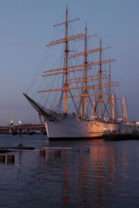 A stunning tall ship docked at sunset in Gothenburg, Sweden, reflecting on calm waters.